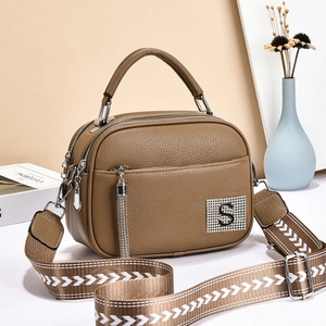Brown textured leather handbag with silver S logo and wide geometric woven strap
