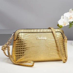 Detail shot of the metallic gold crocodile texture and silver Danbaoly logo on the handbag