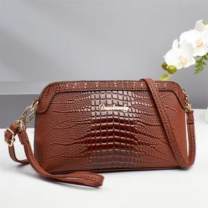 Detail of glossy brown crocodile pattern shoulder bag with gold zipper and logo