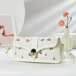 Détail du sac à bandoulière en similicuir blanc avec imprimés cerises et fermoir doré chic