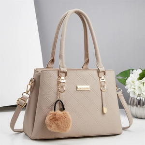 Sac à main élégant en cuir beige grainé avec détails dorés et pompon en peluche