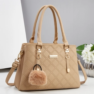 Détail du sac à main matelassé kaki en similicuir texturé avec charm pompon en peluche