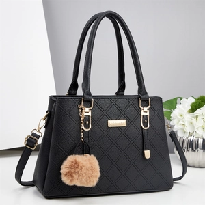 Détail du sac à main noir matelassé avec dorure métallique et breloque pompon marron