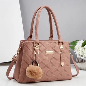 Détail d'un sac à main en cuir matelassé rose avec finitions dorées et pompon