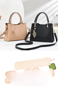 Détail de sacs cabas à texture ondulée en beige et noir avec pendentifs feuilles de perles