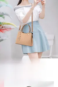 Détail du sac cabas abricot avec rayures verticales, feuilles en métal et perle chic