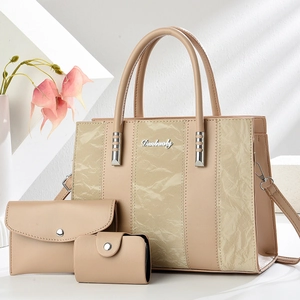 Three-piece beige tote bag set with marble texture and metal logo in a minimalist setting