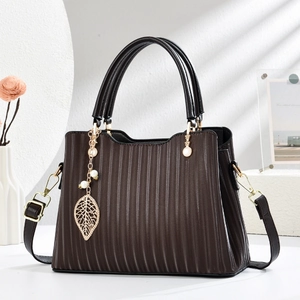 Dark brown textured leather handbag with gold leaf pendant and adjustable shoulder strap