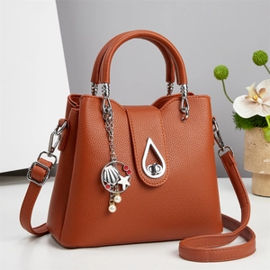 Orange pebble leather bucket bag with seashell charm and adjustable shoulder strap