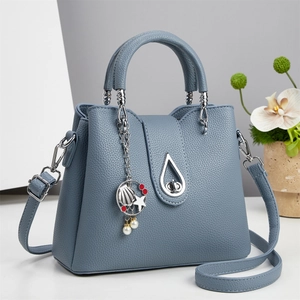 Detailed view of Morandi blue lychee leather bucket bag with silver drop buckle and charms