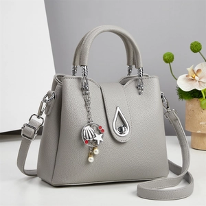 Detail of light gray lychee grain leather bucket bag with sea-themed charms and silver hardware