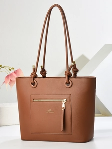 Close-up of brown litchi grain leather tote bag with gold zipper and brand logo detail