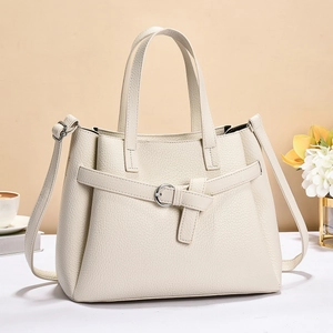 Detail of cream white pebbled leather tote bag with silver hardware on elegant background