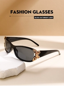 Detail of golden butterfly decor on glossy black frame sunglasses with dark lenses