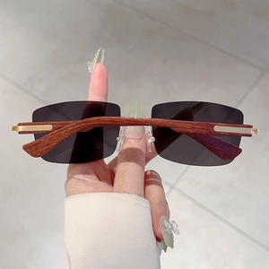 Detail of rimless rectangular sunglasses with wood grain temples and gold metal hinges