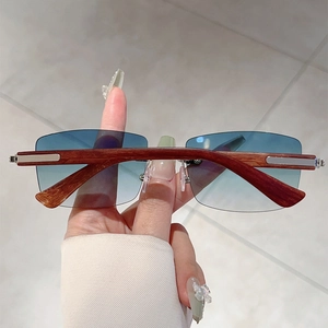 Detail of rimless sunglasses featuring blue gradient lenses and wood grain temple arms