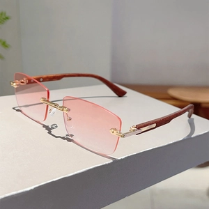Macro detail of rimless sunglasses featuring wood grain temples and pink gradient lenses