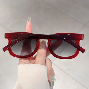 Close-up of red translucent round-frame sunglasses with grey gradient lenses