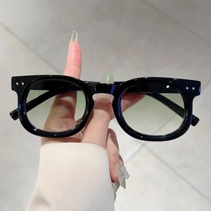 Detail of round black glossy sunglasses frames with silver metal studs and gradient yellow lenses