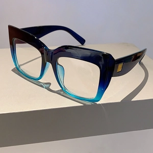 Détail de lunettes carrées œil-de-chat avec monture dégradée bleue et rivets dorés sur la branche