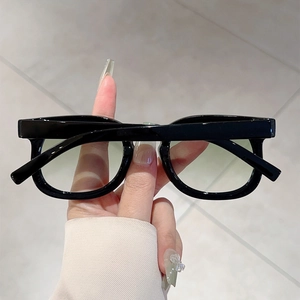 Detail of round frame sunglasses with thick black frames and green gradient lenses