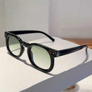 Close-up of black thick frames with light green gradient lenses and silver metal rivets