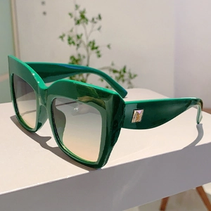 Vue détaillée de lunettes de soleil carrées vertes avec décor en V doré et verres dégradés