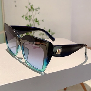 Détail de lunettes de soleil carrées œil-de-chat avec monture dégradée et logo M doré