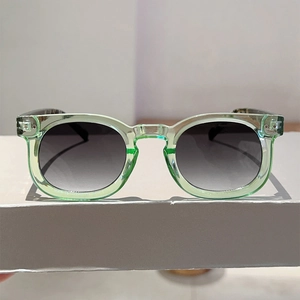 Close-up of translucent mint green sunglasses with silver rivet detail and gradient lenses
