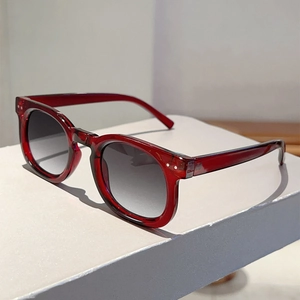 Detailed side view of round wine red sunglasses with silver metal rivets on the frame