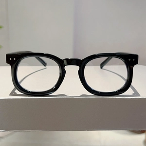 Detailed shot of retro black eyeglass frames with silver rivet accents on a pedestal