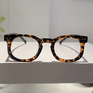 Detailed view of tortoiseshell round eyeglass frames with classic metal rivet accents