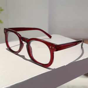 Detail of retro round dark red eyeglasses with silver rivets on thick acetate frame