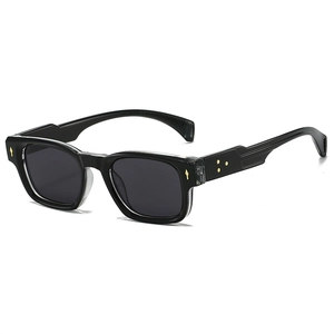 Lunettes de soleil rétro à monture noire et détails fléchés dorés sur fond blanc