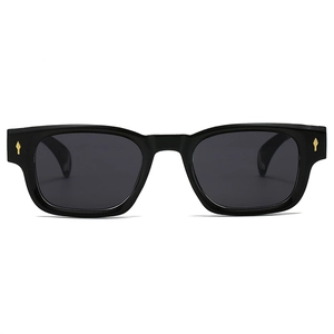 Détail de lunettes de soleil carrées noires avec rivets métalliques dorés en flèche