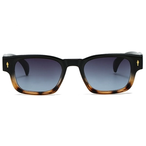 Détail de lunettes de soleil carrées avec clous fléchés et verres bleus dégradés