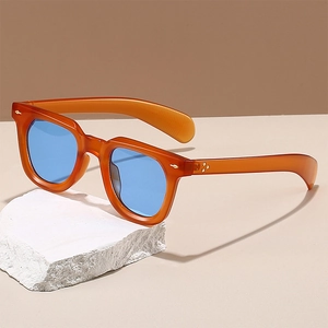 Retro amber eyewear with blue lenses showcased on a minimalist stone display stand