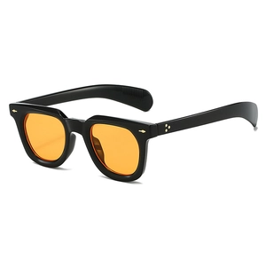 Close-up of retro wide black frame sunglasses with orange lenses and arrow metal rivets