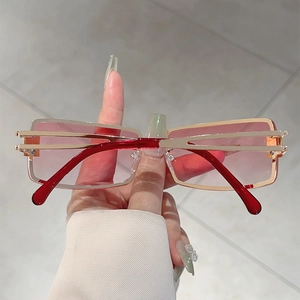 Detail of square gold metal sunglasses with gradient pink lenses and red acrylic arms