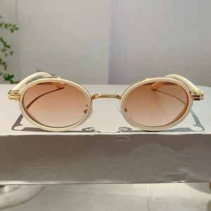 Gros plan détaillé de lunettes de soleil ovales rétro avec monture dorée et bord beige