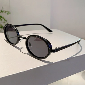 Vue détaillée de lunettes de soleil ovales rétro avec monture noire et plaquettes