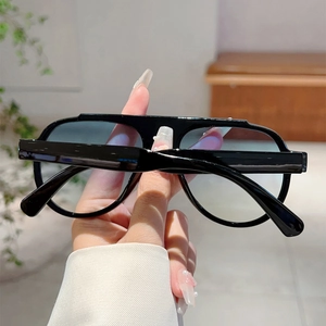 Detail of stylish oversized aviator sunglasses with black frame and blue-green gradient lens