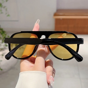 Macro detail of oversized aviator sunglasses with black frames and yellow tinted lenses