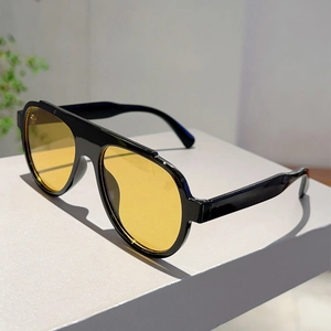 Detail of oversized retro aviator sunglasses with black frames and yellow amber lenses