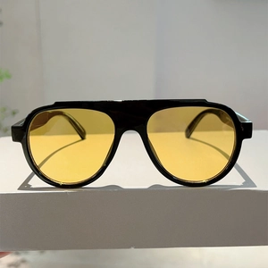 Macro detail of aviator sunglasses with black frame and yellow lenses on a display stand