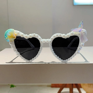 Detail einer herzförmigen Sonnenbrille mit weißen Perlen und schillernden Meerjungfrau-Akzenten