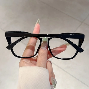 Detail of elegant black cat-eye glasses frame held by hand over marble background