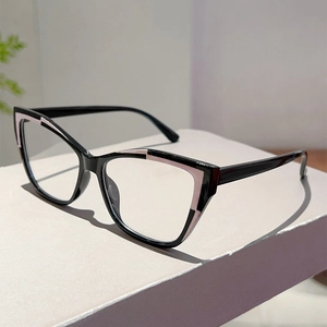 Close-up of elegant black and pink cat-eye glasses frames on a minimalist gray surface