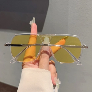 Close-up of oversized aviator sunglasses with transparent frames and yellow lenses