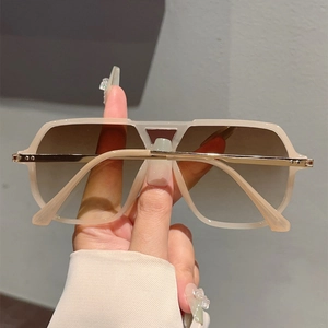 Detail showing oversized champagne square frame sunglasses with gold hinge accents